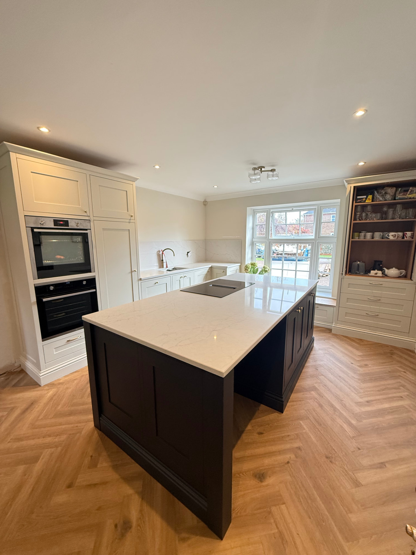 Classic cream in-frame kitchen with dark painted island and herringbone oak flooring