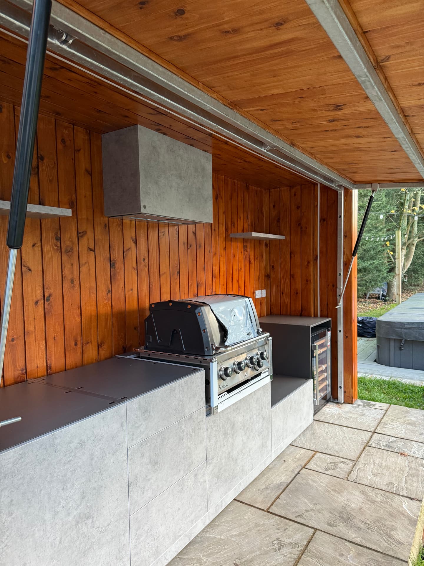 Outdoor bespoke kitchen with concrete-effect cabinetry, built-in grill and wine fridge